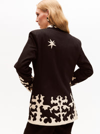 Back shot of the embroidered blazer, highlighting the star motif at the top and the symmetrical cream appliqué detail along the hem and shoulder area.