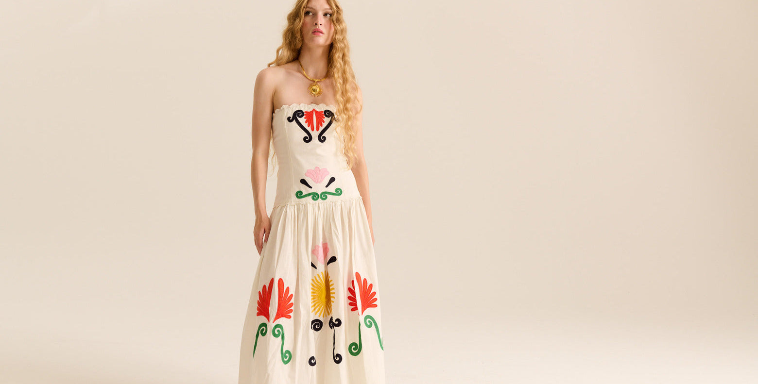 Woman wearing a long dress with colorful abstract designs on a beige background
