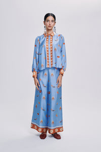 Carolina K palazzo pants in flowing fabric, wide-leg style with a vibrant, patterned design, worn by a model in a casual setting.