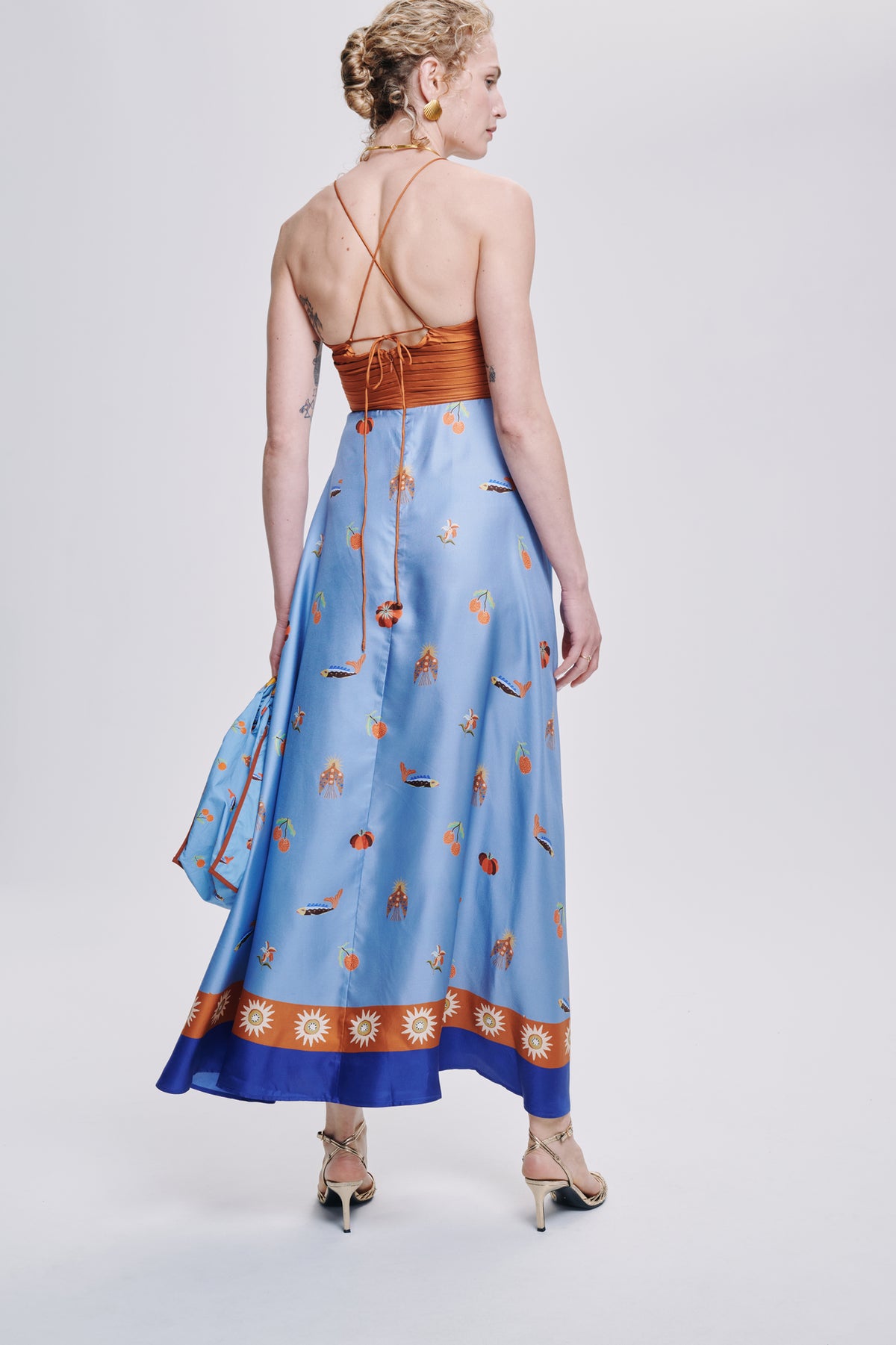 Carolina K Joyce dress in vibrant fabric, stylish design, displayed on a hanger with a colorful background.