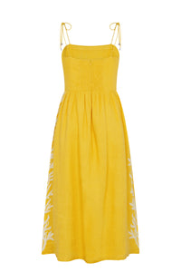 Yellow linen midi dress with adjustable shoulder ties, a smocked back bodice, and a flowing skirt. Features white embroidered botanical motifs along the sides.