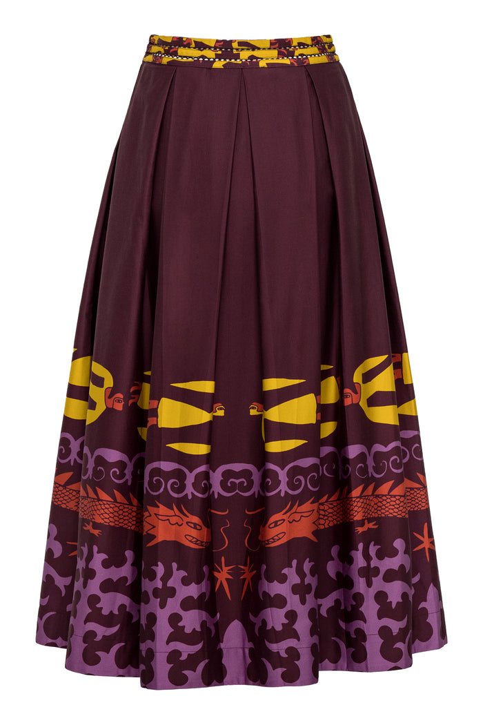 A full, high-waisted A-line skirt in deep maroon featuring a bold multicolor print along the hemline. The print includes stylized yellow human figures, red dragons, and swirling purple motifs, finished with a wide waistband featuring a mix of yellow and maroon patterning.