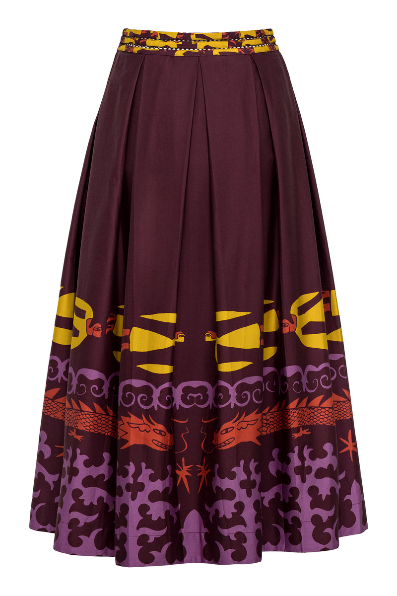A full, high-waisted A-line skirt in deep maroon featuring a bold multicolor print along the hemline. The print includes stylized yellow human figures, red dragons, and swirling purple motifs, finished with a wide waistband featuring a mix of yellow and maroon patterning.