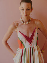 Close-up of a multicolored striped spaghetti-strap dress with a deep V-neckline and beaded necklace.