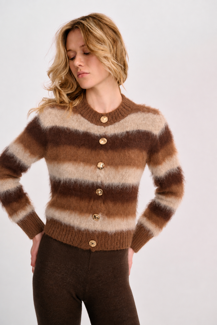 Model wearing the Albor Cardigan, a fuzzy striped knit in cream, camel and chocolate brown with gold-tone buttons.