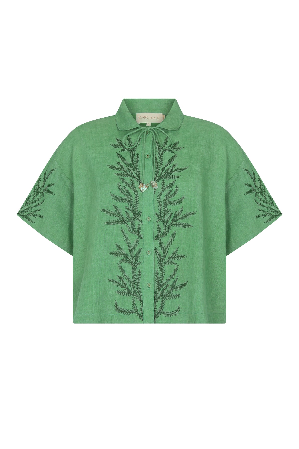 Relaxed-fit linen shirt in a fresh mint hue featuring tonal botanical embroidery along the front and sleeves. Finished with a pointed collar, button-front closure, and shell-inspired tie detail at the neckline.
