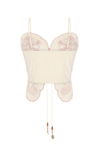 Back view of the off-white embroidered top showcasing adjustable shoulder straps, a smocked elastic back panel for comfort, and scalloped edges outlined with contrast embroidery. Beaded tie cords add a decorative finishing touch.
