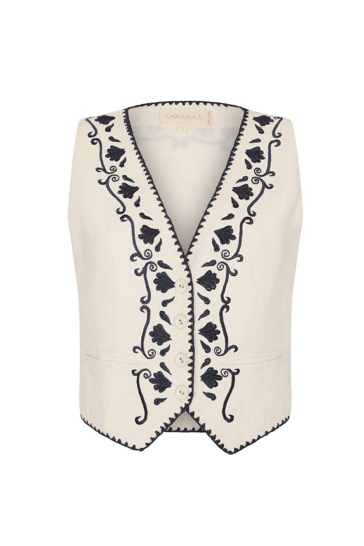 Front view of a cream sleeveless vest with a deep V-neck, front buttons, and navy floral embroidery along the neckline and front panels.