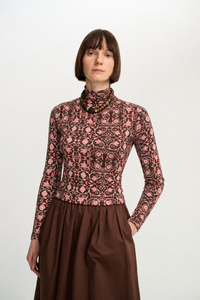 Front view of a model wearing the printed long-sleeve turtleneck with a brown skirt and statement beaded necklace.