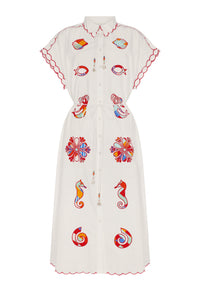 Off-white midi shirt dress featuring a classic collar, button-front closure, flutter sleeves, and an adjustable drawstring waist accented with beaded tassels. Colorful marine-inspired appliqué motifs, including seashells, fish, seahorses, and floral medallions, add a playful coastal touch.